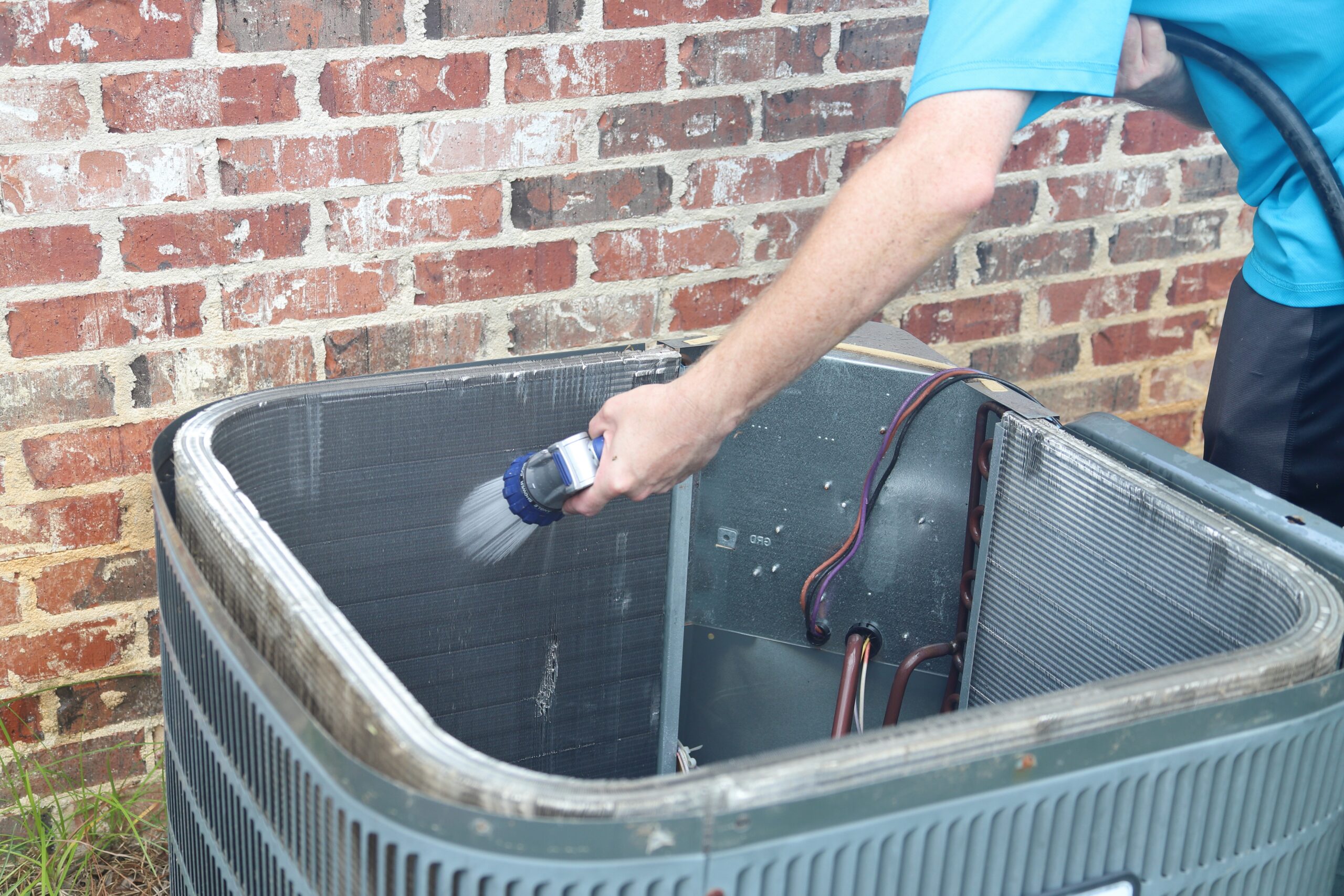 Using hose to clean condenser unit